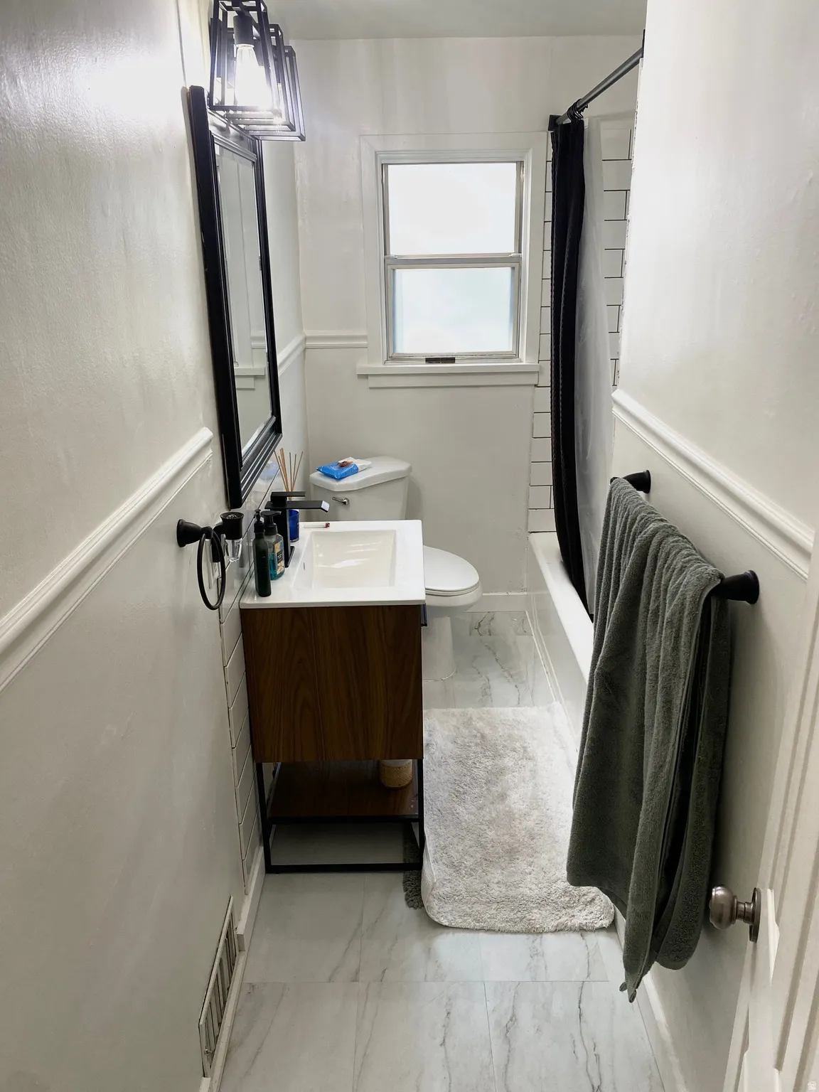 Bathroom featuring light marble finish floors, vanity, and shower / bath combo with shower curtain