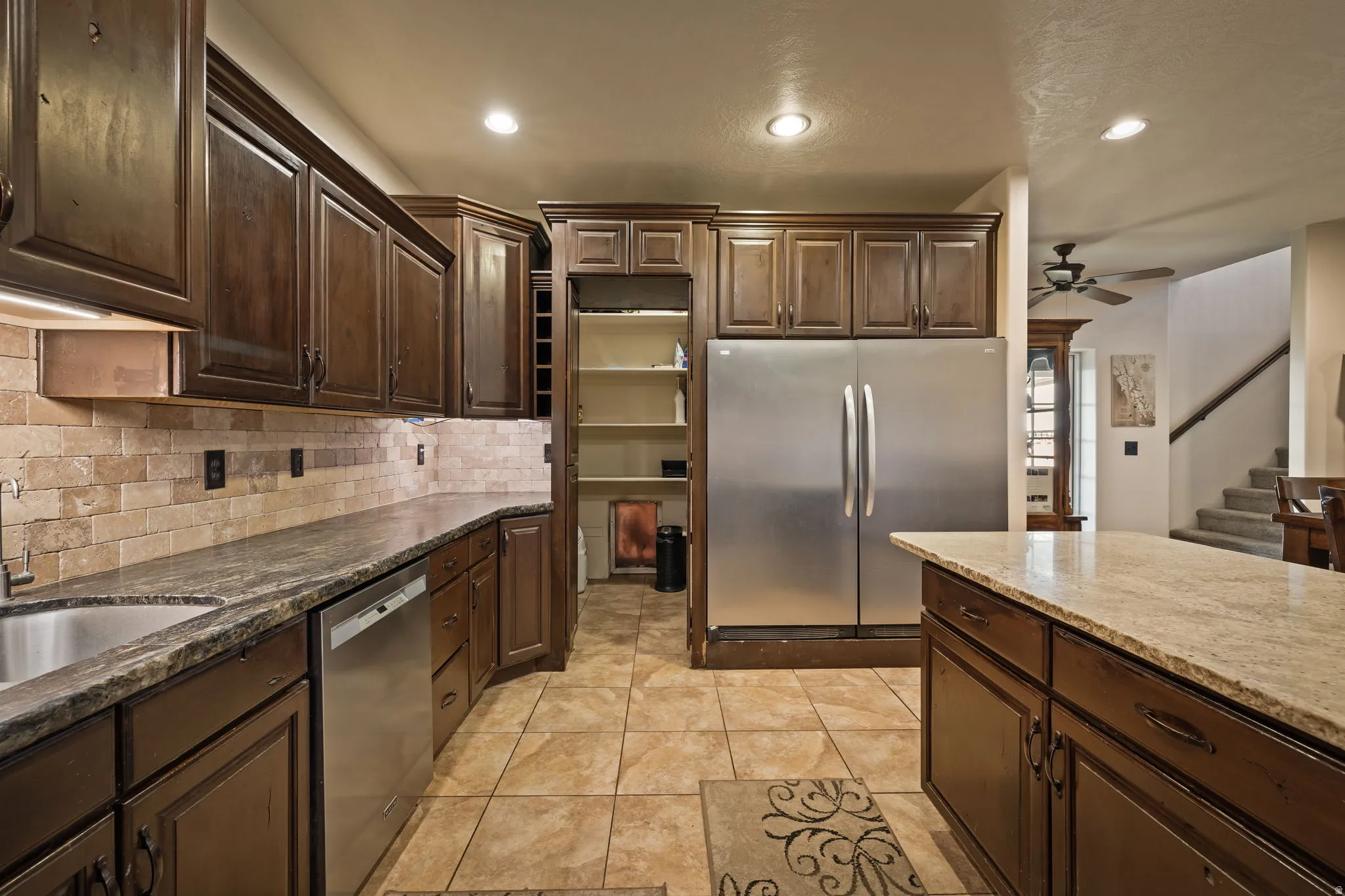 Kitchen with dark brown cabinetry, appliances with stainless steel finishes, recessed lighting, dark stone countertops, and decorative backsplash