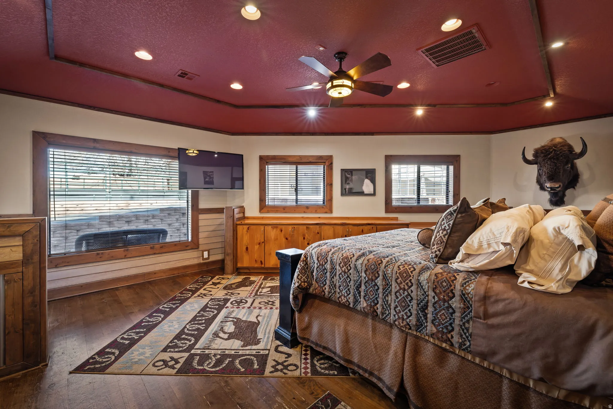 Bedroom with a tray ceiling, hardwood / wood-style floors, a textured ceiling, a ceiling fan, and recessed lighting