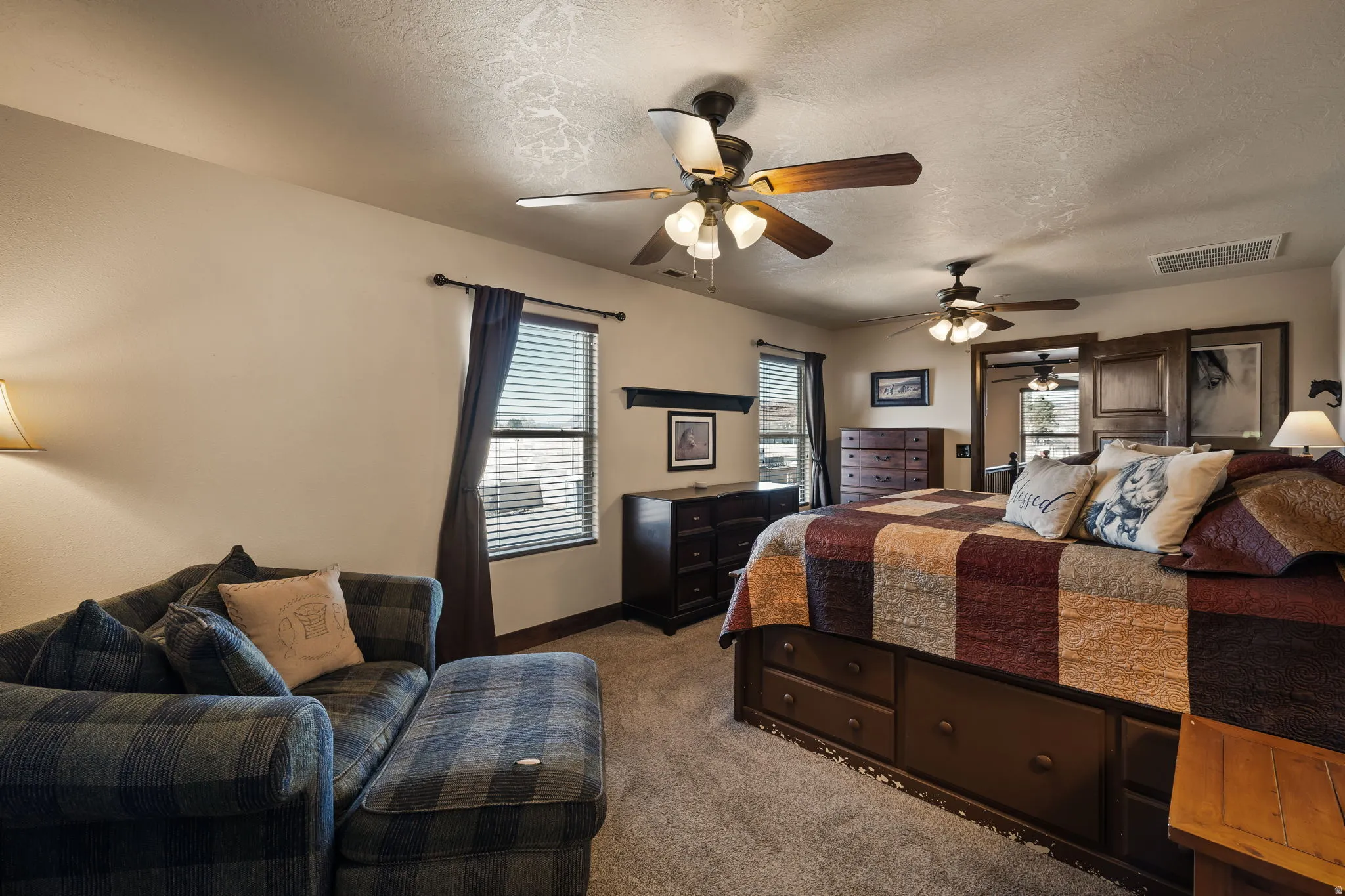Bedroom featuring a textured ceiling, light colored carpet, and a ceiling fan
