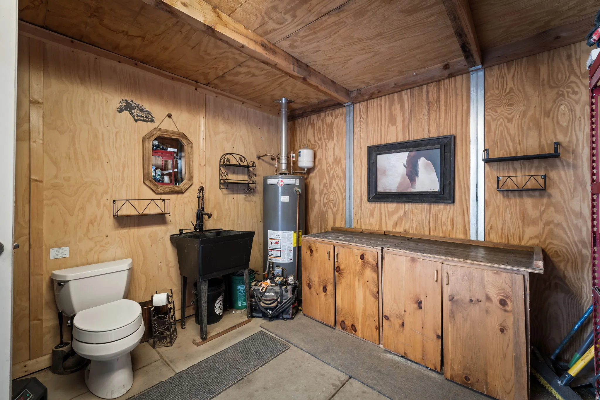Bathroom with wooden walls, concrete floors, wood ceiling, gas water heater, and vanity