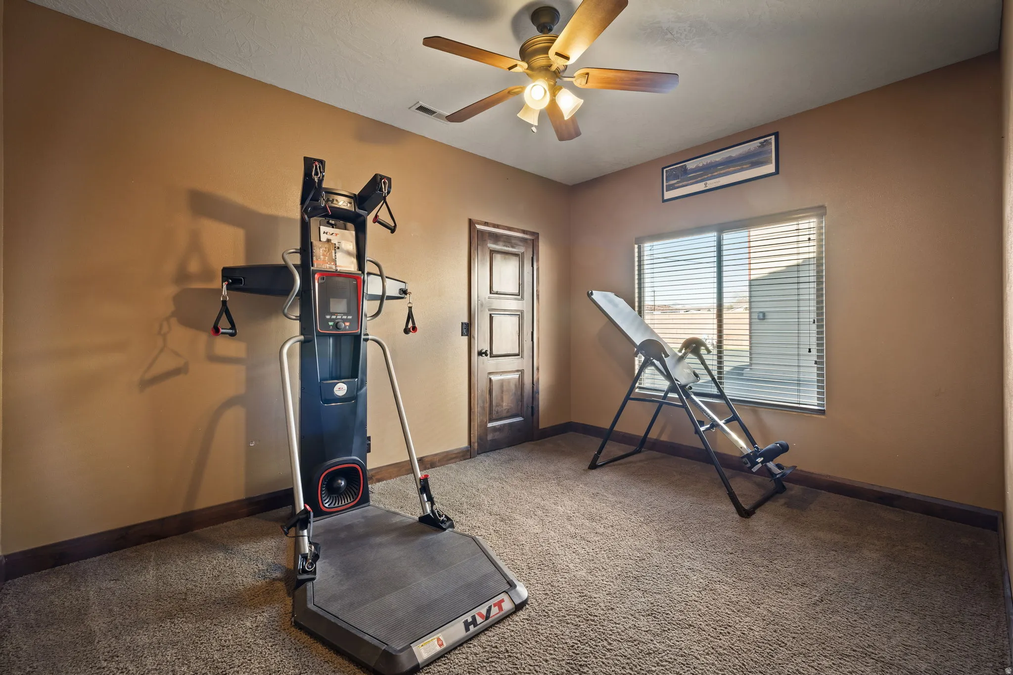 Workout room featuring dark colored carpet and a ceiling fan