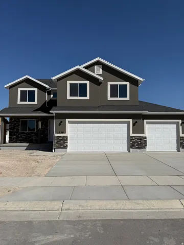 Modern exterior with dark stucco, stone accents, and a multi-car garage