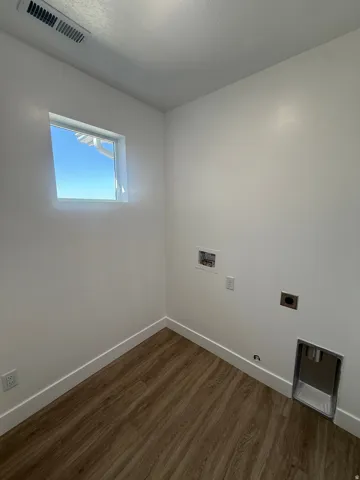 Wood-finish flooring with white baseboards and a bright window