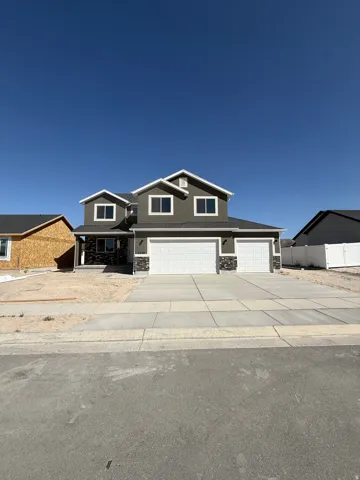 Two-story exterior with horizontal siding and stone accents, dual attached garage doors, and a concrete driveway