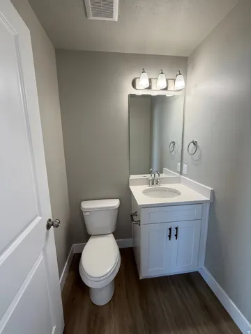 White vanity with a white countertop and integrated sink, chrome faucet, and dark hardware