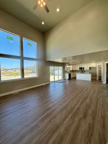 Vaulted ceilings with recessed lighting and a ceiling fan, wood-finish flooring, and large windows