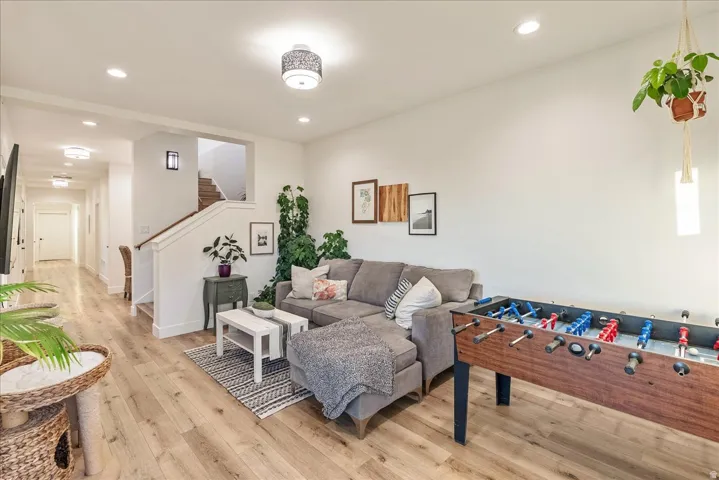 Living area with light wood finished floors, recessed lighting, and stairs