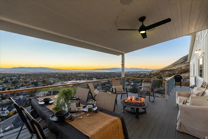Deck at dusk featuring a ceiling fan, a mountain view, a fire pit, and area for grilling