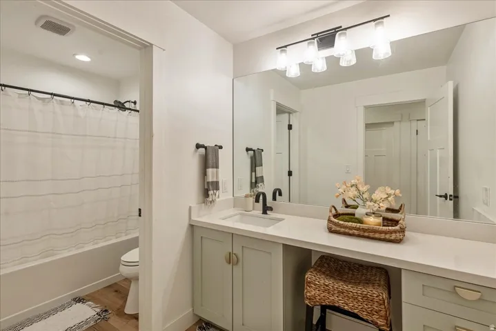 Bathroom with vanity, shower / bath combo with shower curtain, and light wood-type flooring