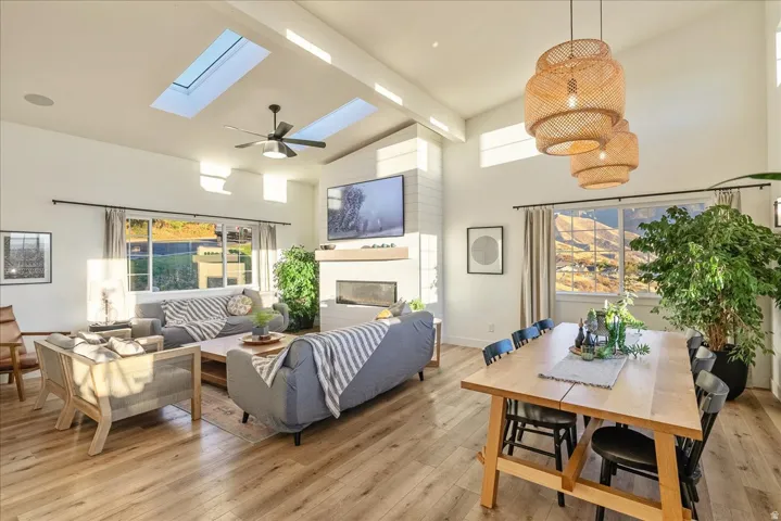 Living area with a fireplace, light wood-style floors, a skylight, ceiling fan, and plenty of natural light