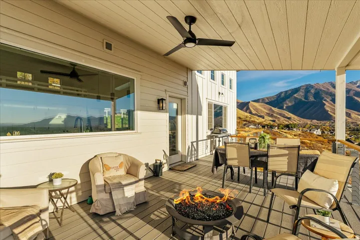 Deck with a mountain view, outdoor dining area, a ceiling fan, and a fire pit