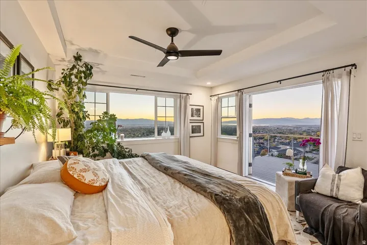 Bedroom with a ceiling fan, a raised ceiling, and a mountain view