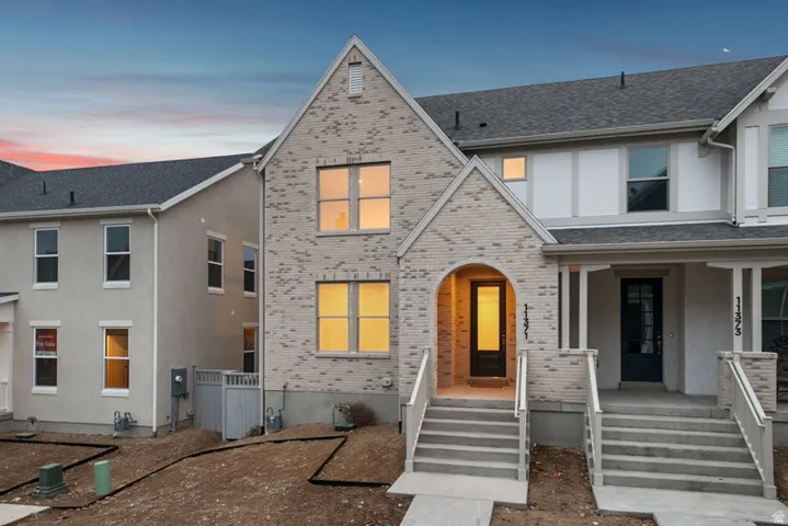 View of front of property featuring brick siding, covered porch, and a shingled roof