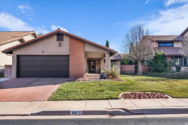 View of front of property featuring driveway, a front lawn, stucco siding, and an attached garage