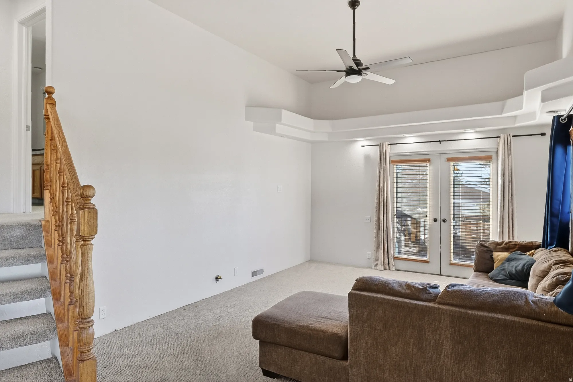 Living room with french doors, carpet floors, stairs, ceiling fan, and high vaulted ceiling
