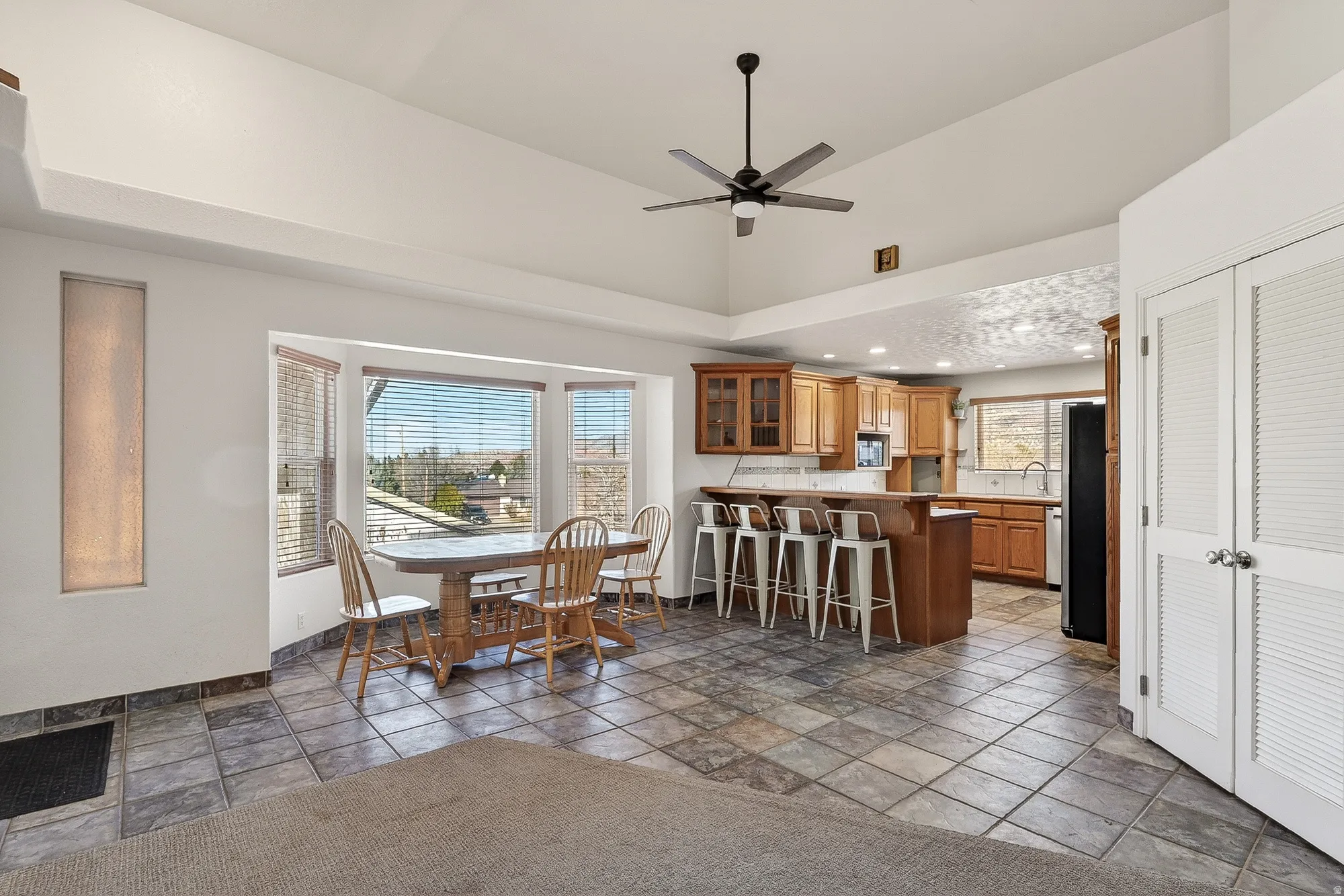 Dining room featuring ceiling fan, stone tile flooring, and recessed lighting