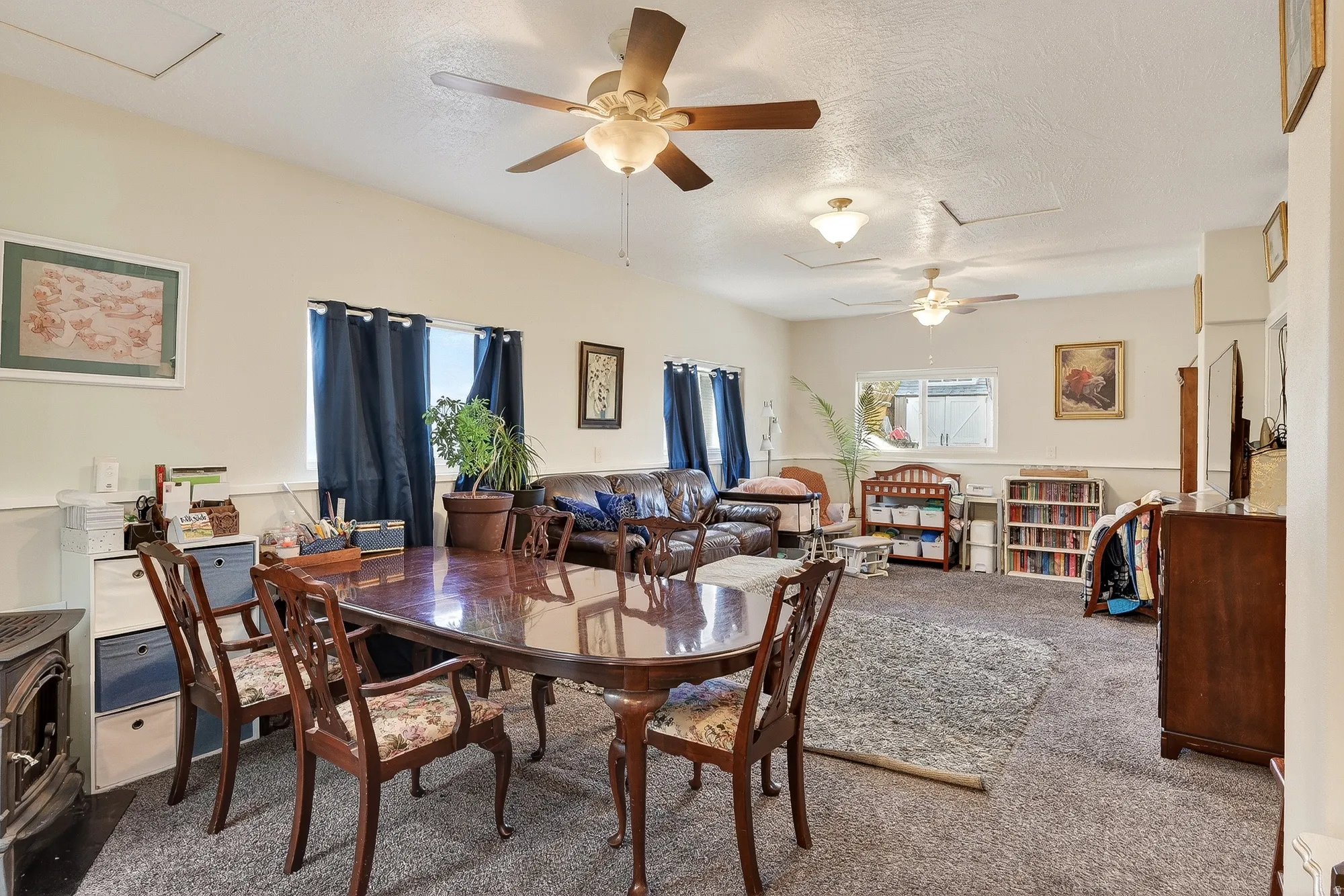Carpeted dining space with attic access, a ceiling fan, and a textured ceiling
