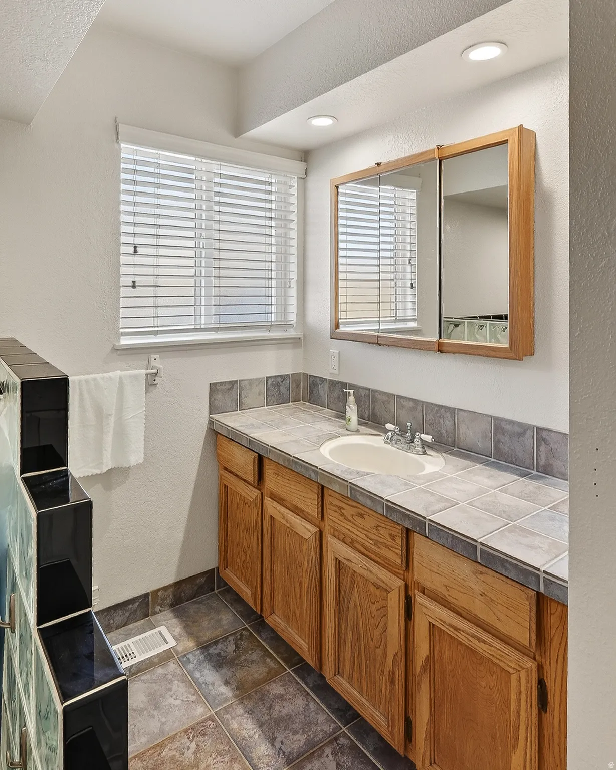 Bathroom with a textured wall, vanity, and a textured ceiling