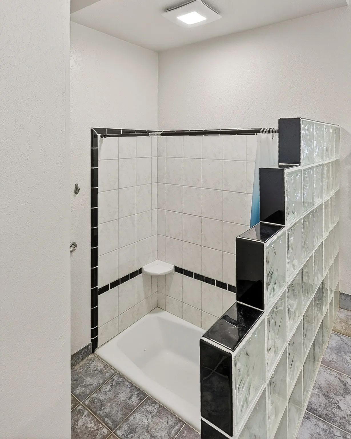 Full bathroom featuring tiled tub and a textured wall