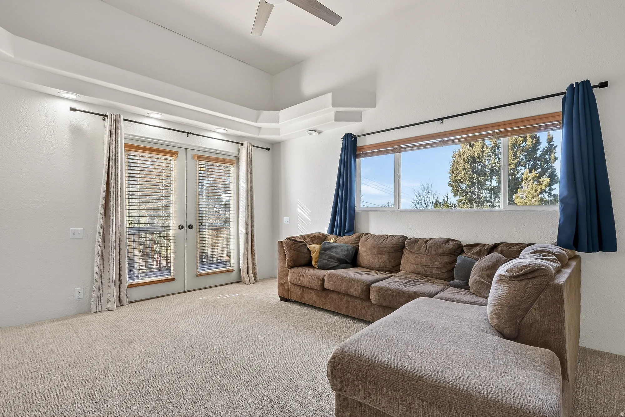 Living area featuring french doors, carpet flooring, and ceiling fan