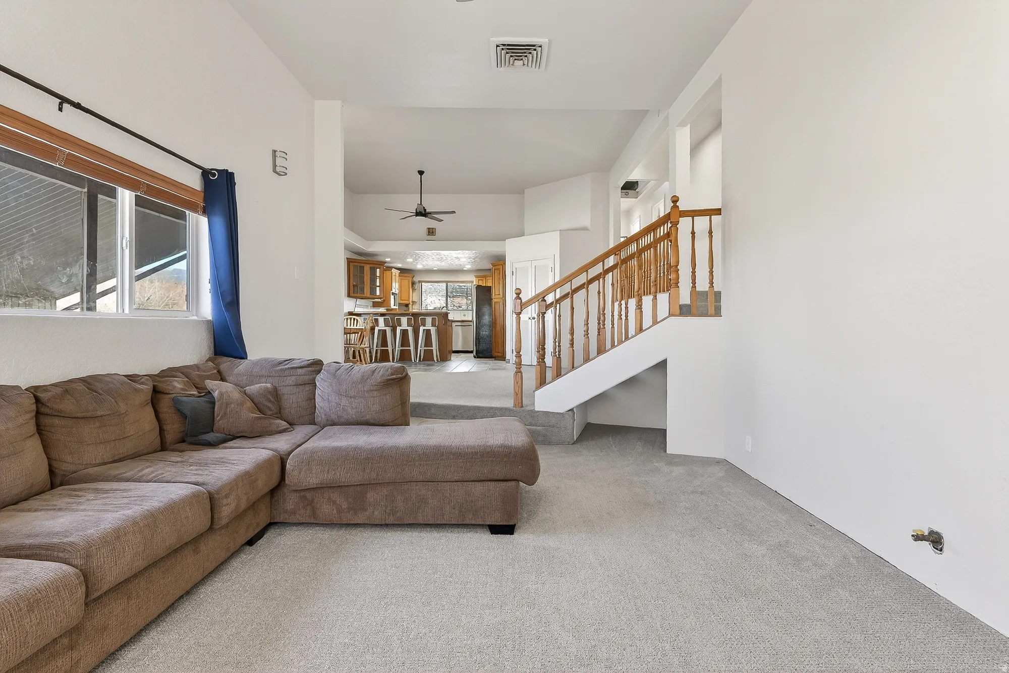 Carpeted living area featuring stairs and ceiling fan