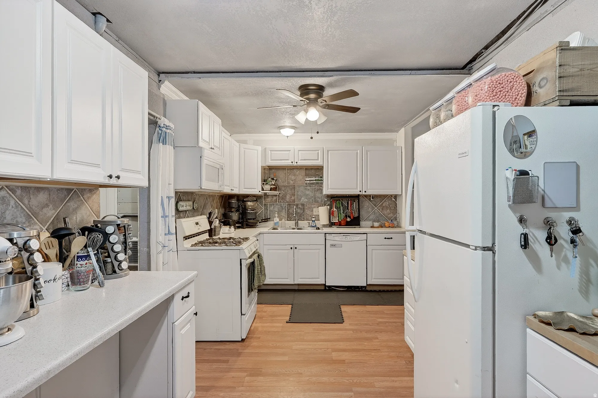 Kitchen featuring white appliances, white cabinetry, light wood finished floors, and light countertops