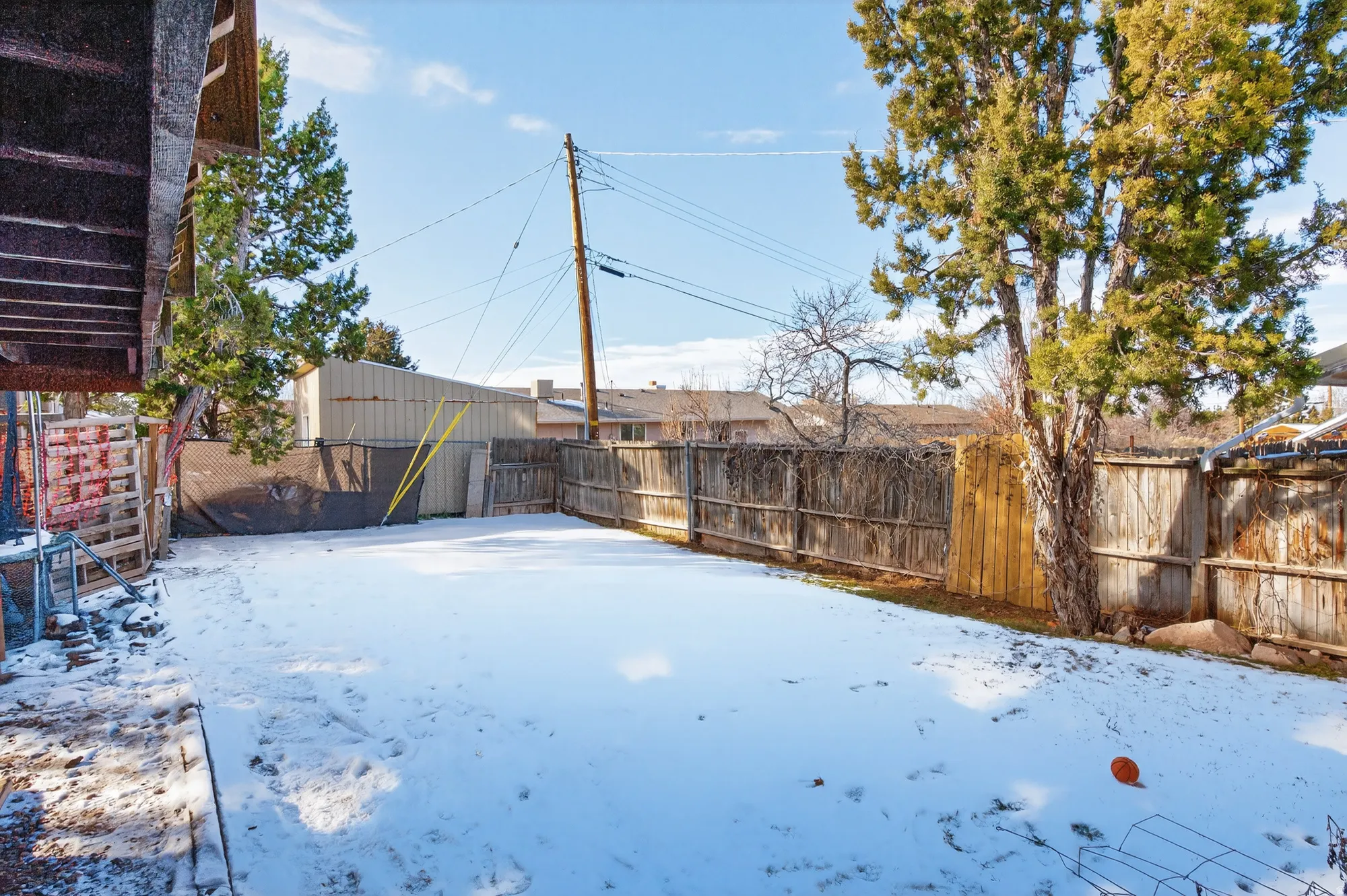 Yard covered in snow with a fenced backyard