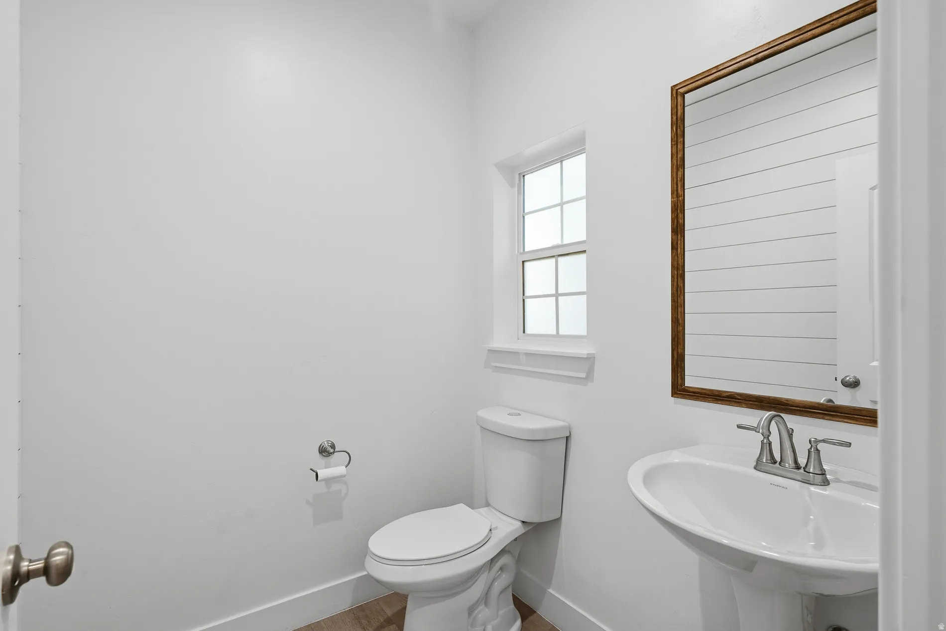 Half bathroom featuring toilet and wood finished floors