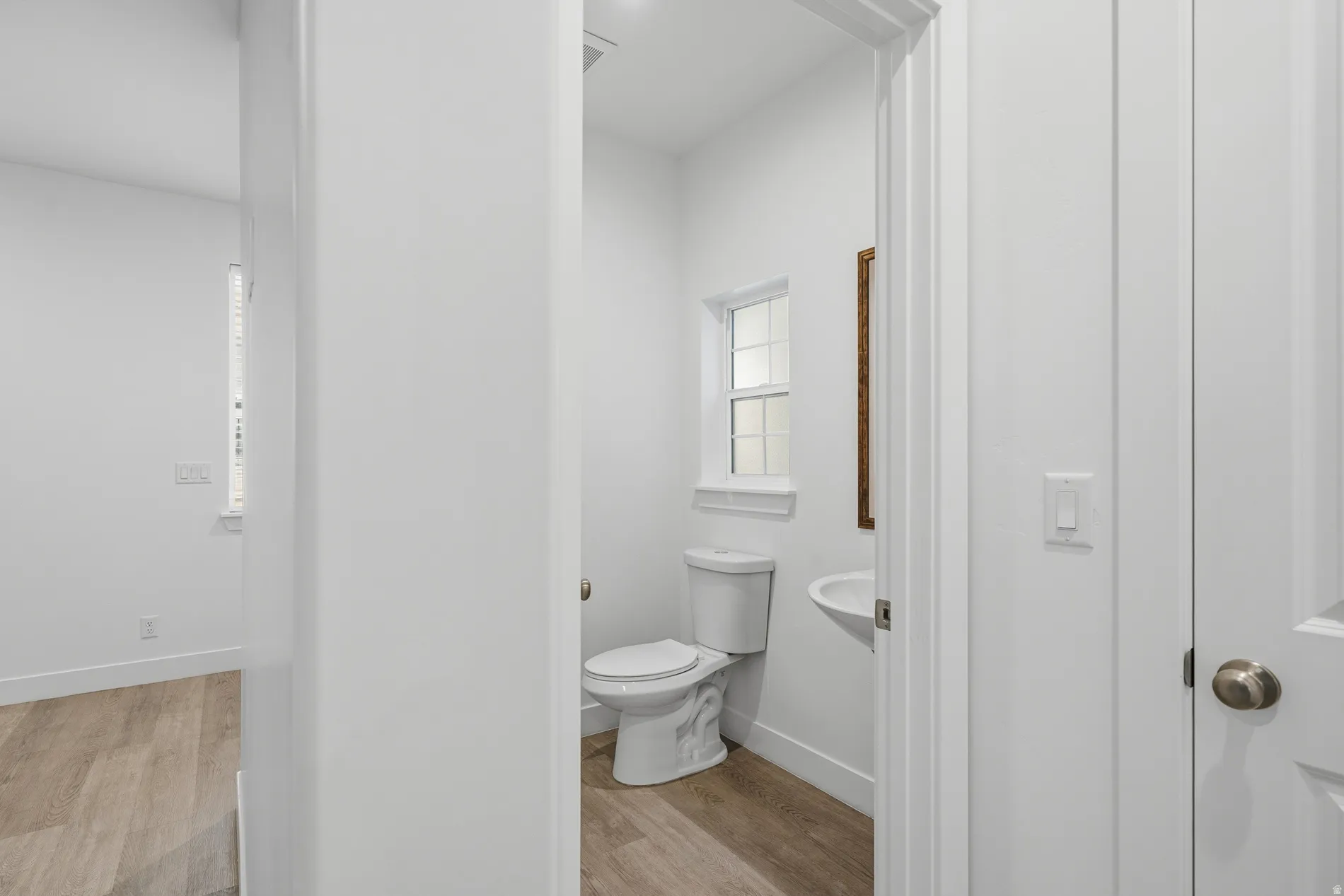 Half bath featuring light wood-type flooring and toilet