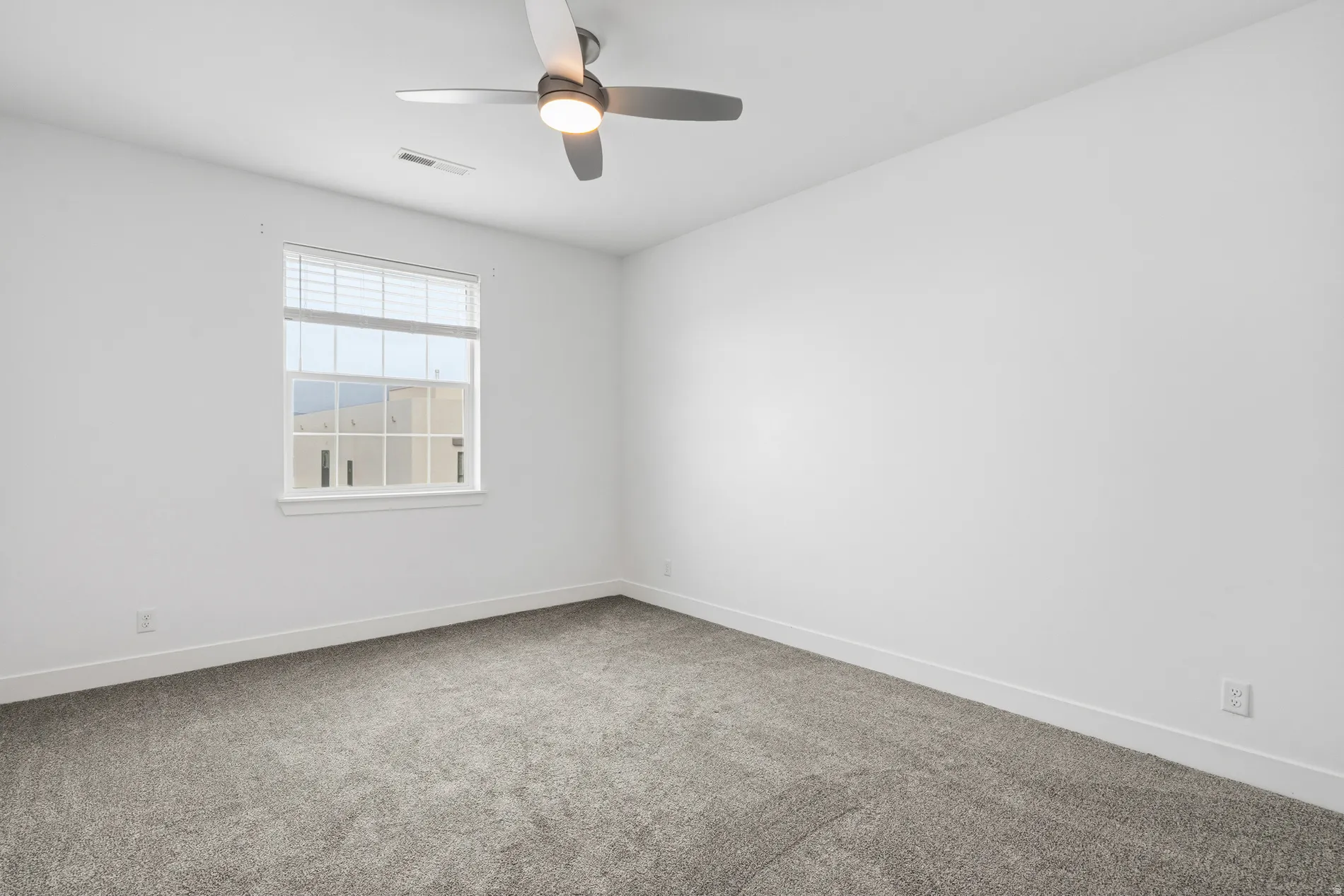 Spare room featuring light colored carpet and ceiling fan