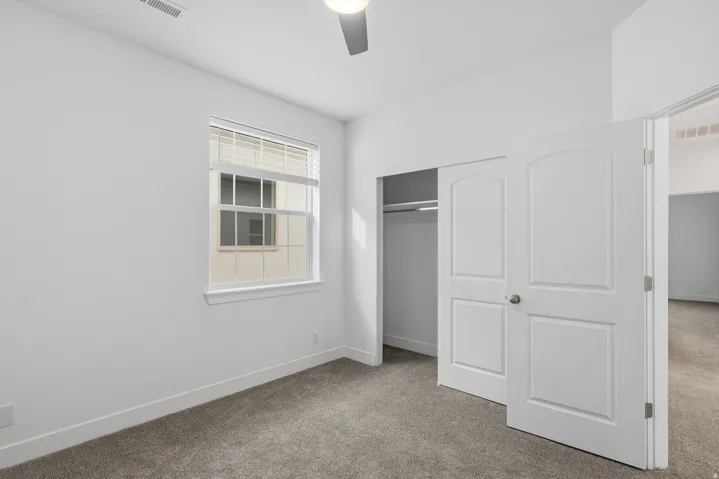 Unfurnished bedroom with carpet floors, a closet, and a ceiling fan