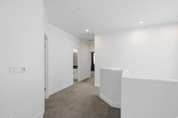Hall featuring an upstairs landing, dark carpet, and recessed lighting