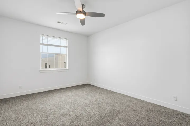 Spare room featuring light colored carpet and ceiling fan