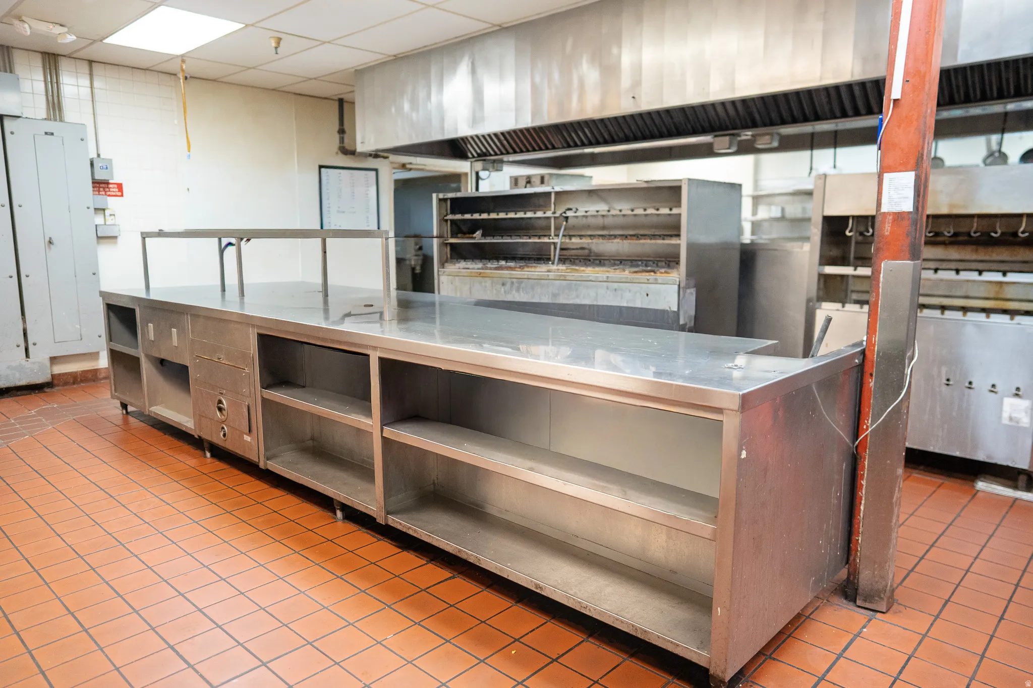 Kitchen featuring stainless steel counters, a paneled ceiling, and ventilation hood