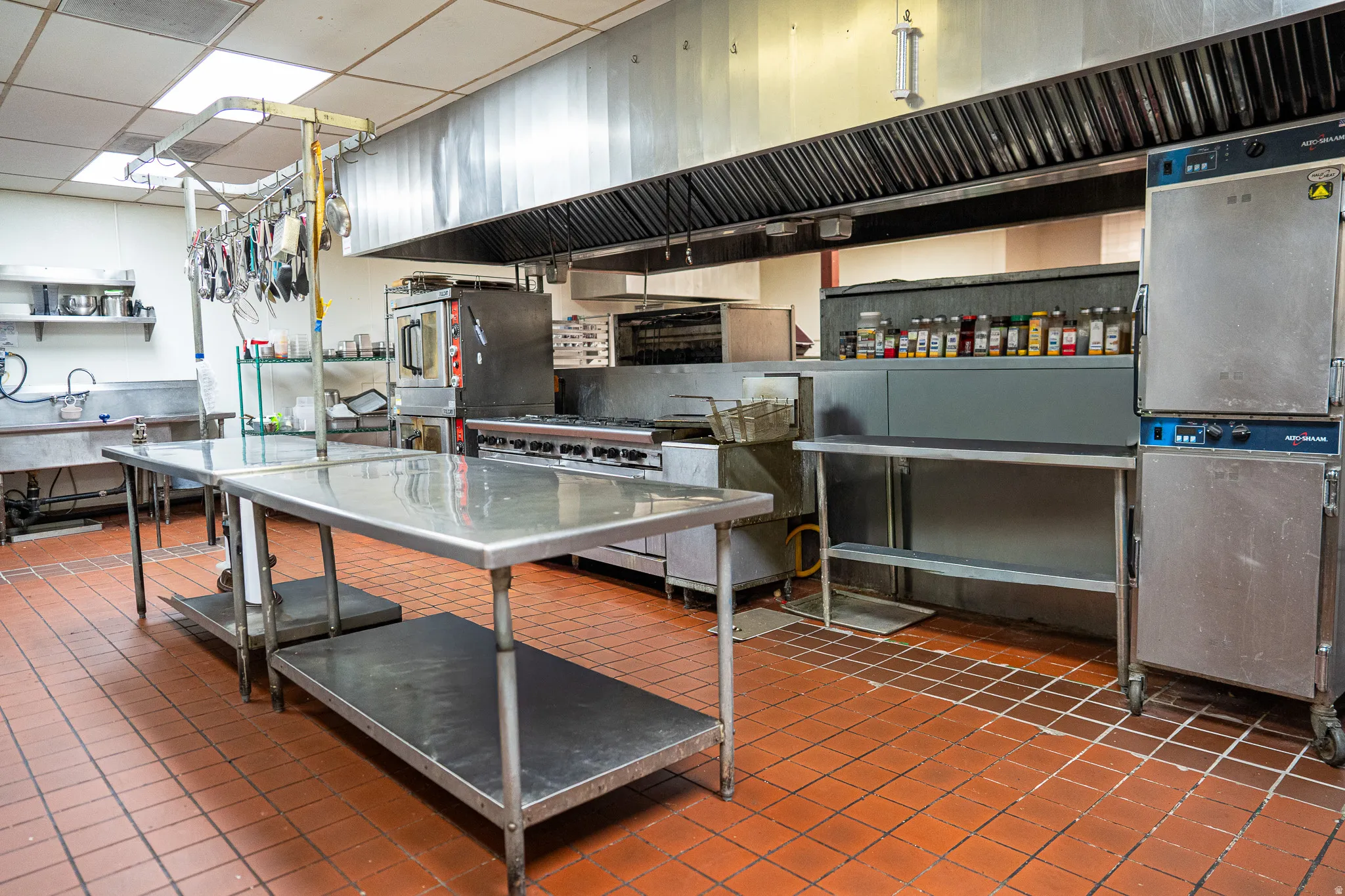 Kitchen featuring under cabinet range hood, a drop ceiling, stainless steel counters, and range with two ovens