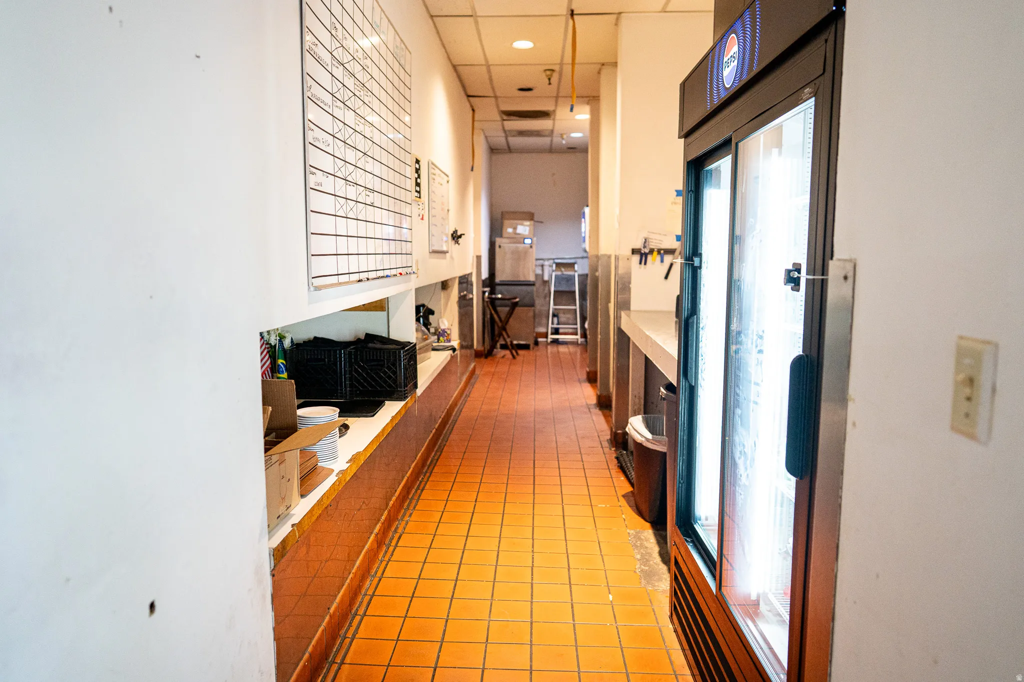 Corridor featuring a paneled ceiling, light tile patterned flooring, and recessed lighting
