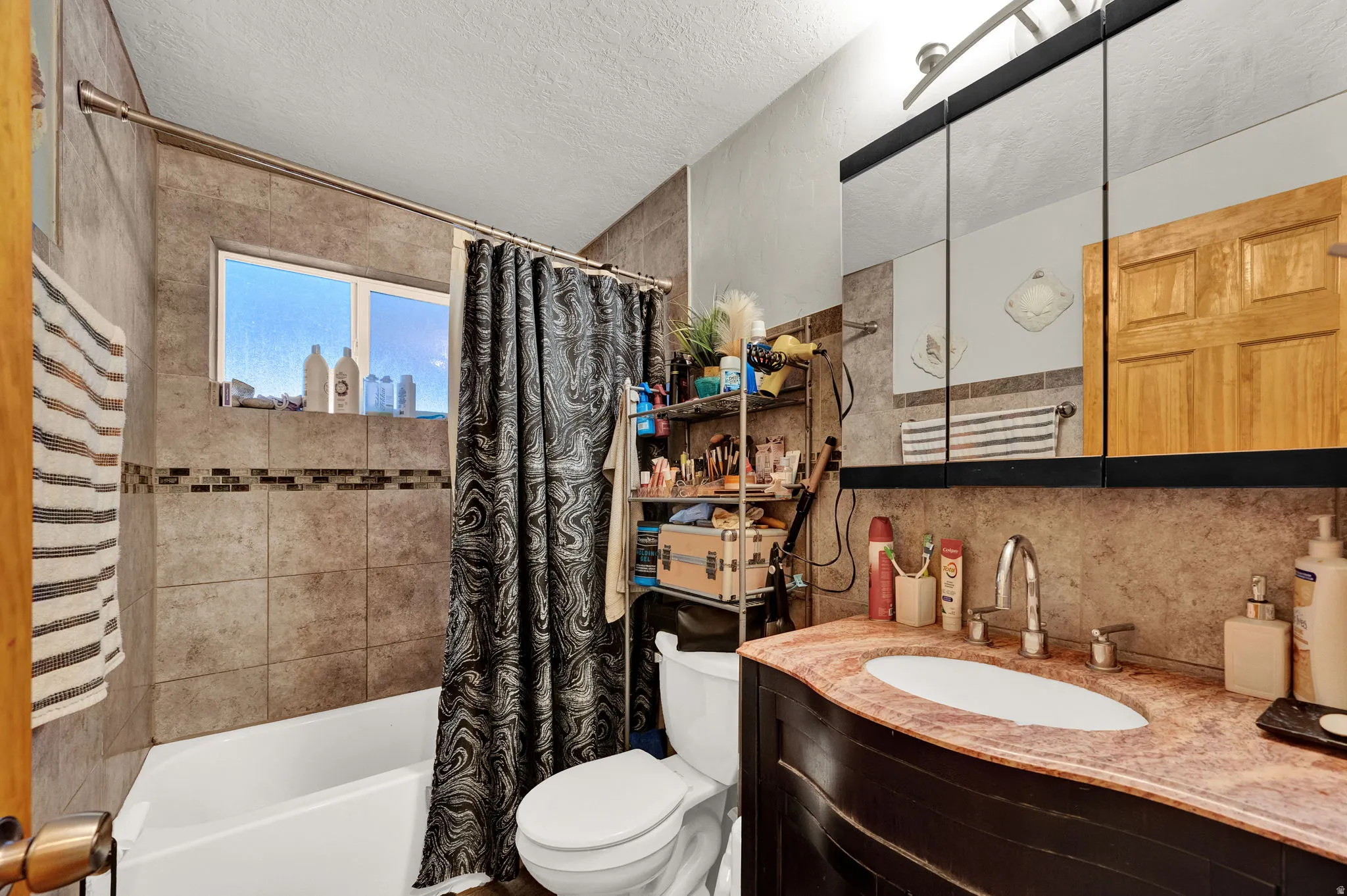 Bathroom with shower / bath combo, vanity, and a textured ceiling
