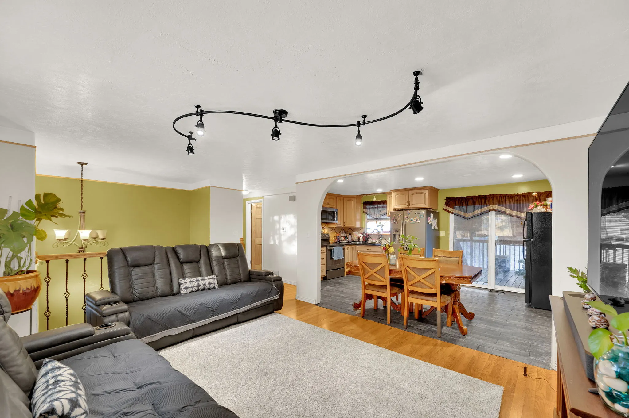 Living room with arched walkways, a chandelier, light wood-style flooring, and recessed lighting