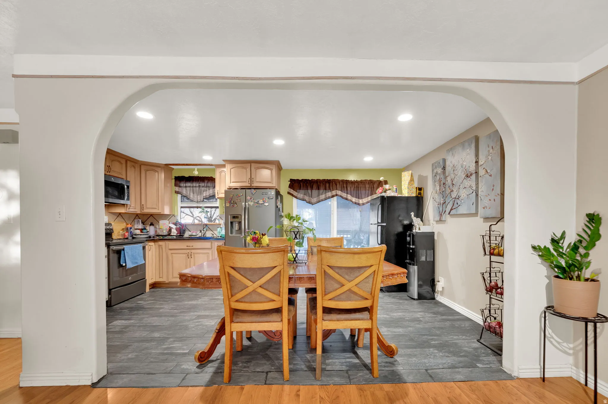 Dining room featuring arched walkways, light wood-style floors, and recessed lighting