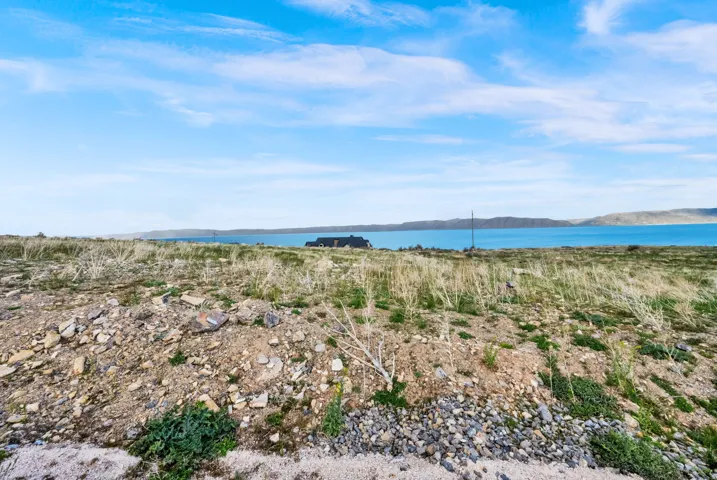 Expansive land parcel featuring natural terrain and distant water body with a visible shoreline