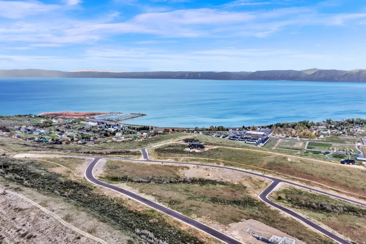 Expansive waterfront property featuring a deep blue lake, surrounding mountains, and paved roadways