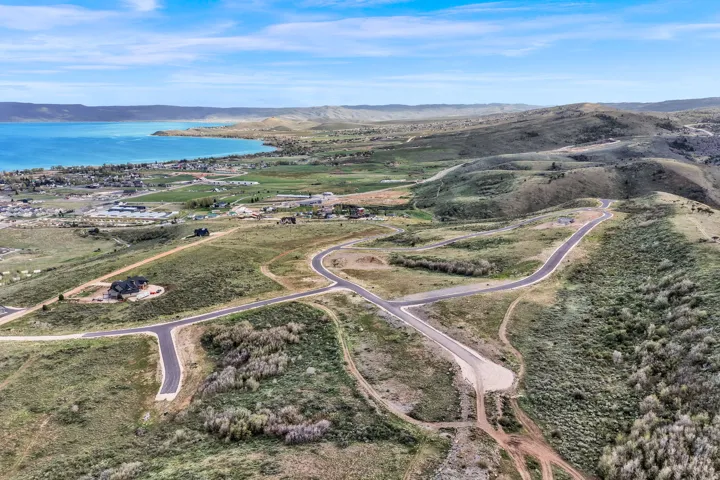 Aerial landscape featuring a large body of water, rolling hills, and a network of paved roads