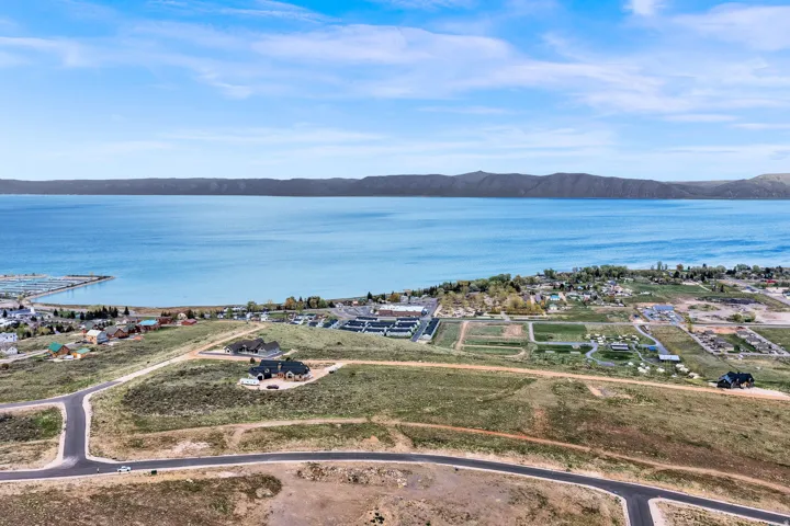 Expansive land parcel featuring existing paved roads and a serene lake backdrop