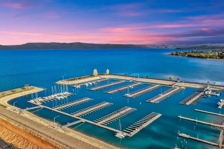 Expansive marina featuring multiple boat slips on vibrant blue waters, framed by distant hillsides and a colorful sky
