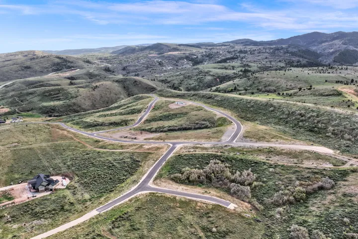 Expansive mountain landscape featuring numerous paved roads and a distant residential structure