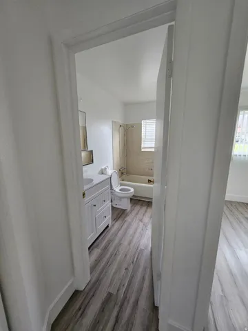 Full bath featuring light wood-type flooring, vanity, and shower / bath combination