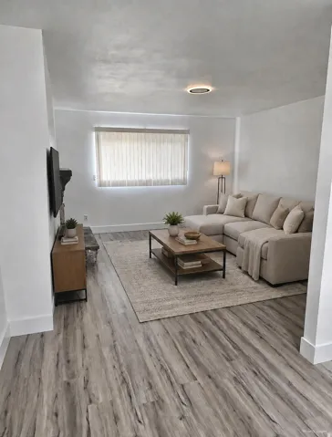 Wood-finish flooring throughout, complemented by a recessed ceiling light and a window with horizontal blinds