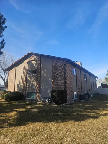 View of side of home featuring brick siding, a lawn, and a chimney