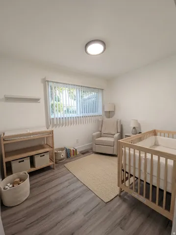 Recessed ceiling light fixture, wood-finish flooring, and a window with horizontal blinds